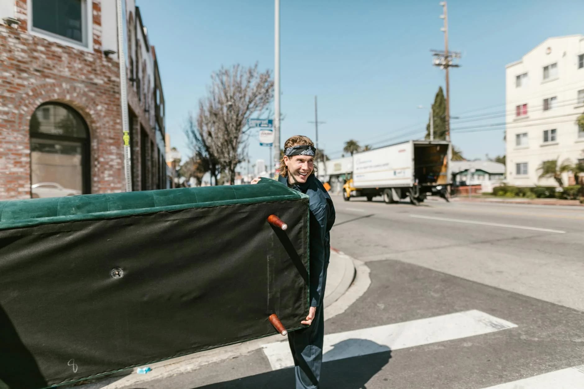A Cheerful Man Carries A Large Couch Acr 3