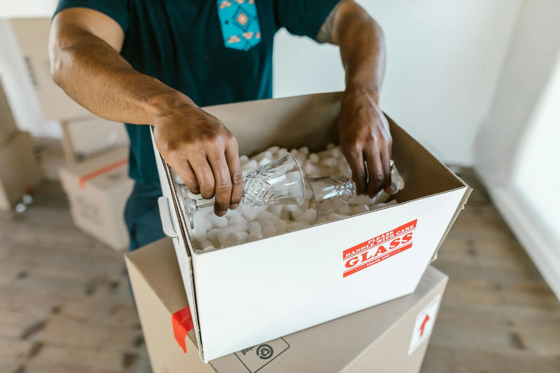 Person Packing Glassware Into Boxes With 1