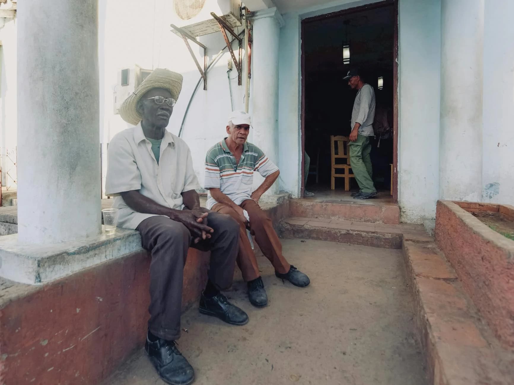 Three Men Seated And Standing By A Doorw 2