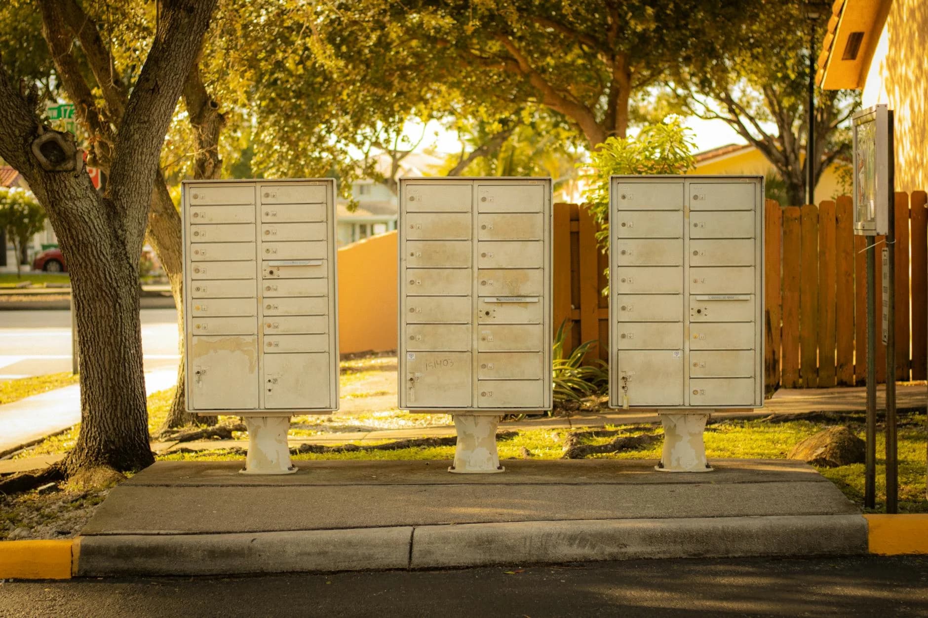 Three Cluster Mailboxes Under Trees In A 2