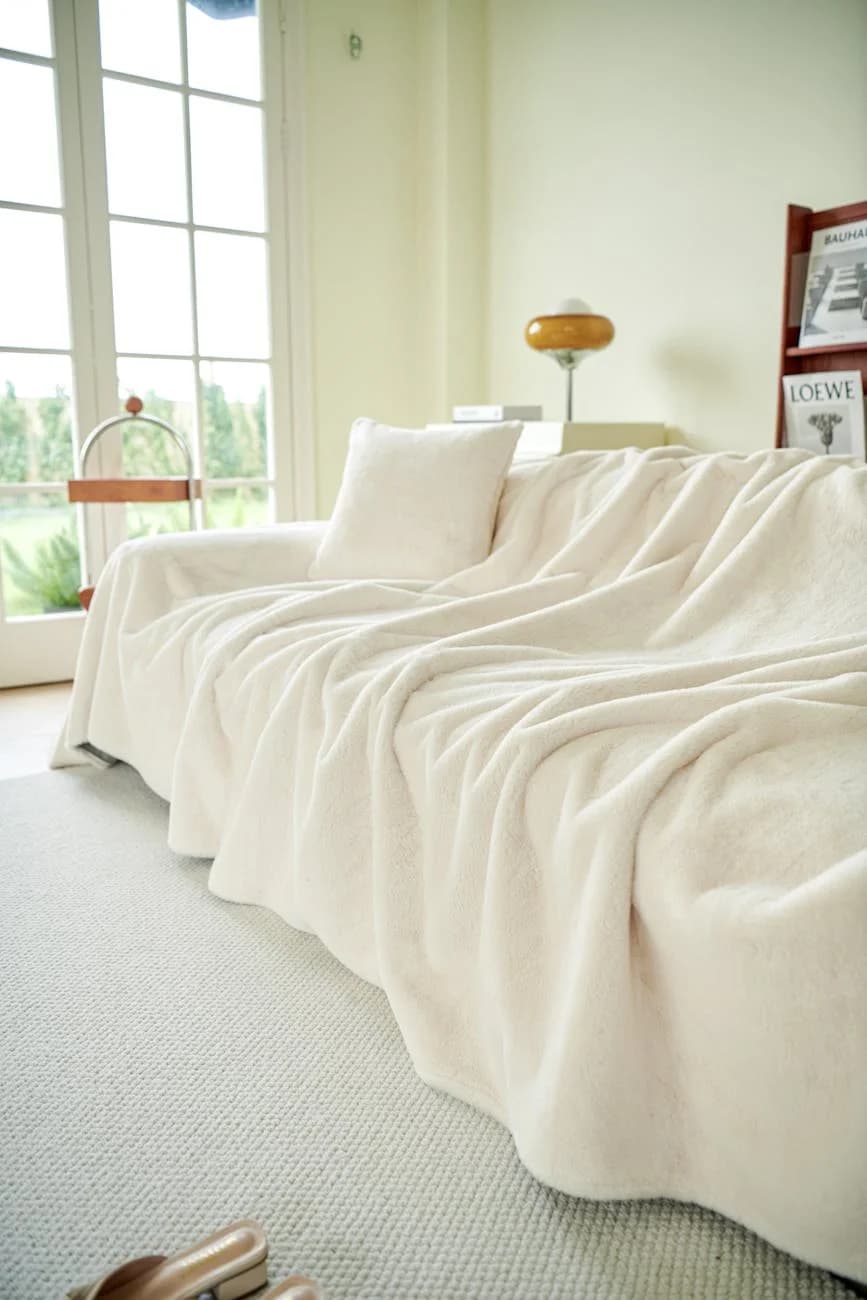 A Cozy Beige Sofa Covered With A Soft Th 1
