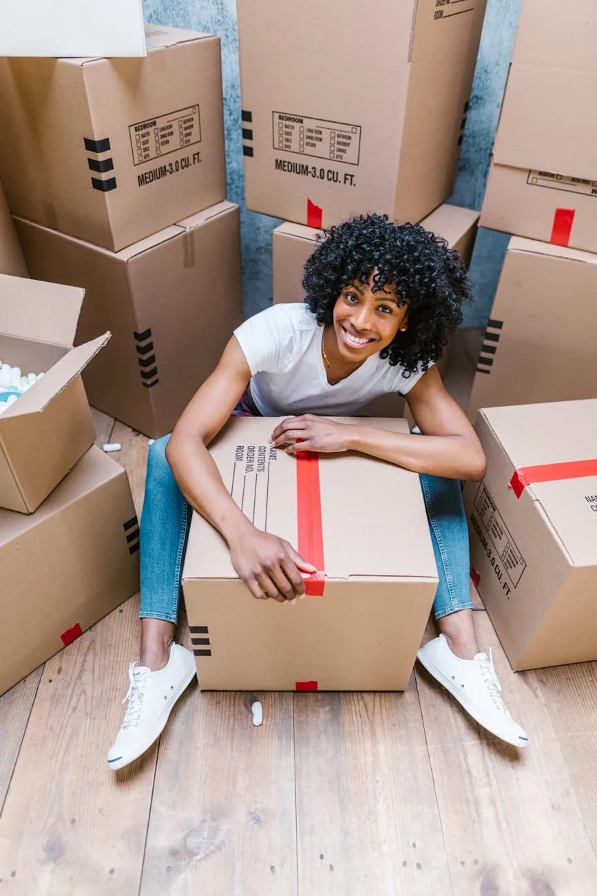 Happy Woman Sitting Among Boxes While Pa 1