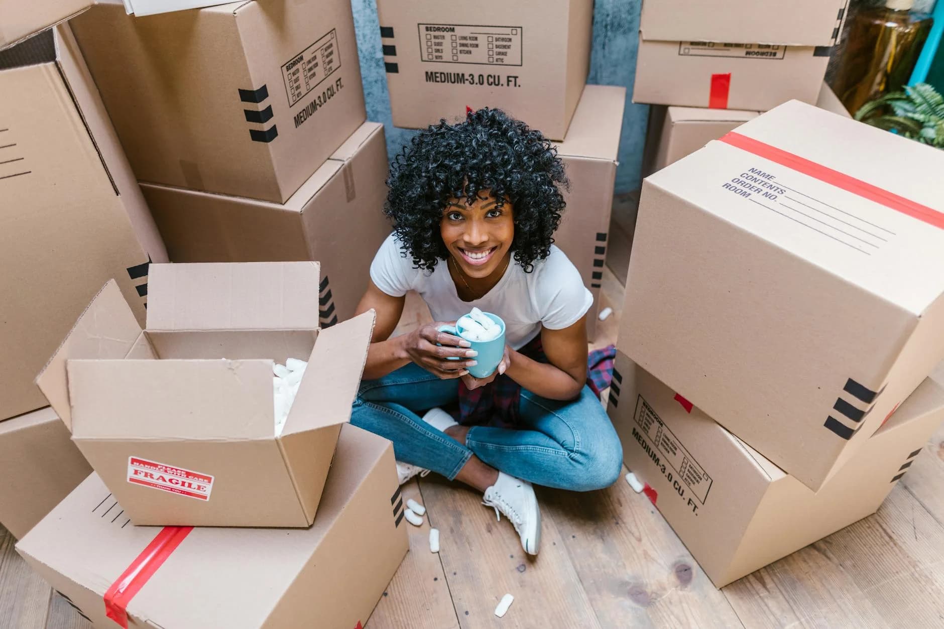 A Woman Sitting Among Moving Boxes With 3