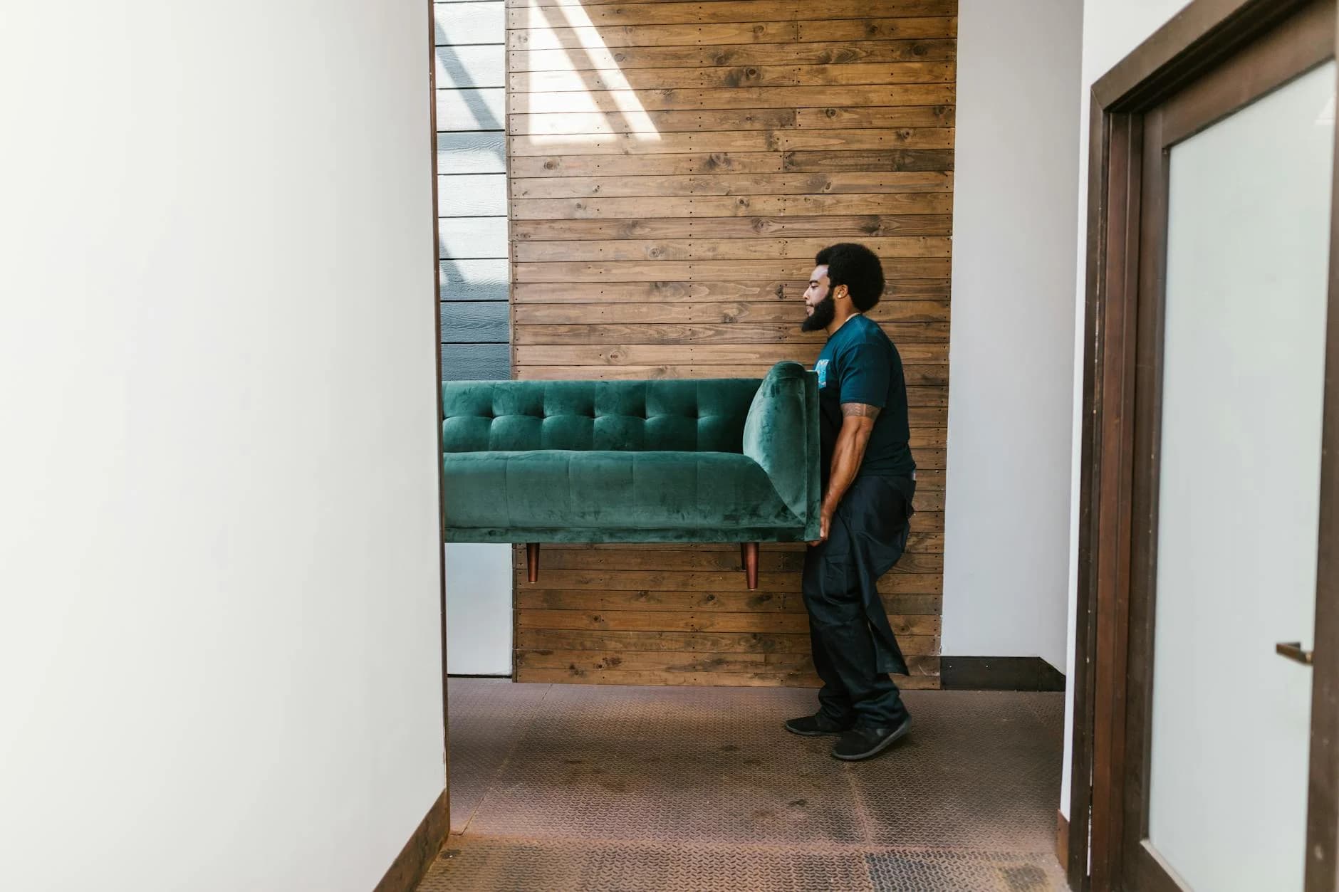 A Mover Carries A Green Sofa Indoors Sho 3