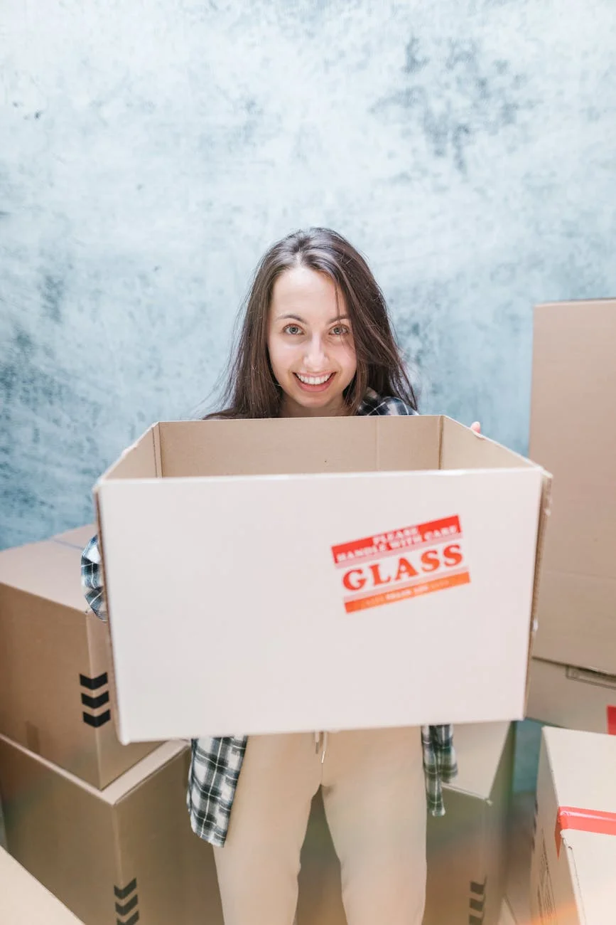 Smiling Woman Holding A Box Marked Fragi 1
