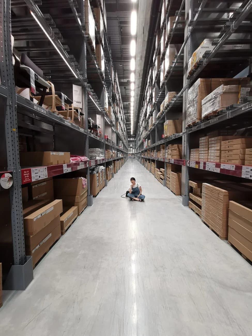 An Asian Woman Sits In A Large Warehouse 4